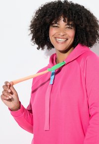 Růžová mikina s kapucí a šňůrkami v oranžové, zelené a modré barvě, vyrobená z měkké látky, s volným střihem a klokankovou kapsou.