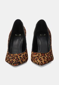 Zapatos de tacón alto con estampado de leopardo, punta afilada, tela de piel texturizada y ribete de cuero negro. Interior de zapato plano y tacones redondeados.