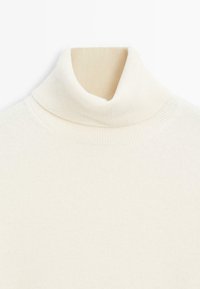 Kremowy sweter z golfem, wyróżniający się prążkowaną fakturą, miękkim dzianinowym materiałem oraz dopasowanym fasonem z wysokim kołnierzem.