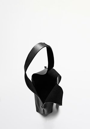 Zwarte leren tas met een brede opening, platte band en gladde textuur. Heeft een minimalistisch ontwerp zonder zichtbare hardware of patronen.