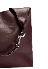 Burgundowa skórzana torba tote o zorganizowanej formie, z zaokrąglonym szczytem i metalowym zapięciem na pasku. Gładka tekstura z minimalnymi akcentami.