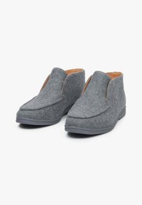 Szare filcowe kapcie z usztywnioną cholewką, okrągłym noskiem i minimalistycznym designem. Posiadają beżowe wnętrze i szaro-rubberną podeszwę zapewniającą przyczepność.