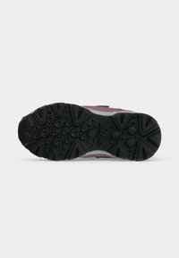 Semelle d’une chaussure avec une semelle en caoutchouc noir présentant des motifs circulaires et triangulaires, affichant le nom de la marque Geox au centre.