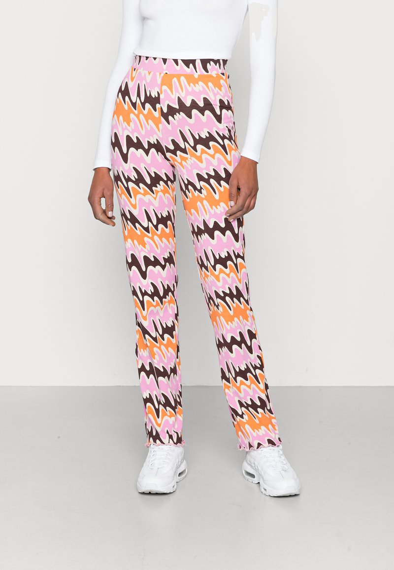 Calças coloridas de cintura alta com um padrão em zig-zag em rosa, laranja, castanho e creme. Feitas de tecido elástico, com um ajuste justo.