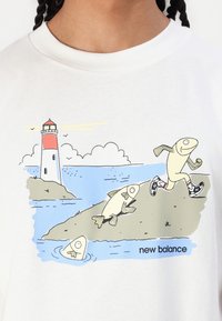 T-shirt branca com um gráfico de cartoon colorido de um farol, dois peixes e uma personagem peixe a correr com ténis, acompanhado do texto "new balance".