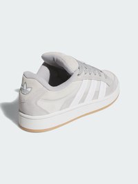 Grå semsket sneakers med hvit tre-stripes design, polstret tunge og gummisåle med et logopatch på hælen.