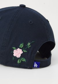 Navy baseball cap featuring pink floral embroidery and a blue tag labeled 'LA' on the back side.