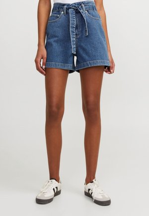 Jeanshorts med hög midja, knytbälte och avslappnad passform. Blå färg, med uppvikta fållar och framfickor, i kombination med vita sneakers.