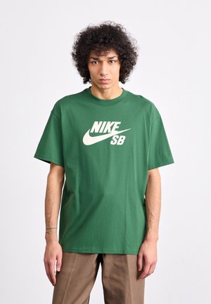 Green cotton t-shirt with a large white Nike logo and "SB" text on the front. Short sleeves and a relaxed fit. Smooth texture.