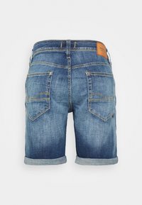 Pantalones cortos de mezclilla con un degradado de claro a oscuro. Dobladillo enrollado, dos bolsillos traseros y un parche de cuero en la cinturilla. Detalles de costura en los bolsillos.