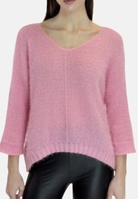 Maglione rosa lavorato a maglia con scollo a V, maniche a tre quarti e finitura testurizzata. L'orlo è leggermente più lungo sul retro con dettagli a coste.