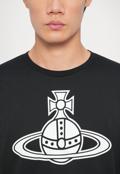 Musthave mustrik, millel on suur valge graafika, mis kujutab krooni ja sõrmust. Ümar kujund, lühikesed varrukad, sile kangas.