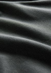 Tessuto strutturato di colore grigio scuro, con un delicato motivo a coste e pieghe ondulate, che mette in evidenza il suo materiale morbido e l'aspetto stratificato.