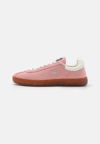 Zapatilla de ante rosa con un tacón de piel crema, cordones blancos y una suela de goma translúcida. Presenta un pequeño logo en el lado exterior.