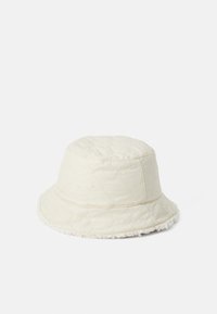 Bucket hat made of quilted cream fabric, featuring a soft, textured brim edged with plush material, and a rounded crown design.