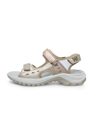 Open-toe sandals with a beige and metallic rose gold finish, adjustable straps, perforated design, and a white, textured sole.