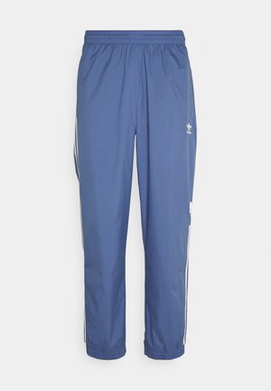 Niebieskie spodnie dresowe Adidas z elastycznym pasem i ściągaczami, białe paski po bokach oraz logo Adidas na górnej, lewej części uda.