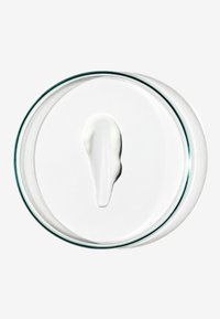 Vit grädde på en cirkulär glasfat med en slät, glansig yta, mot en ljus bakgrund som framhäver textur och konsistens.