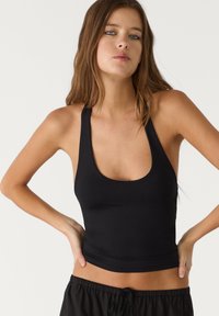 Black sleeveless top with a wide scoop neck and fitted design, made from smooth stretchy fabric. Length falls just above the waist.