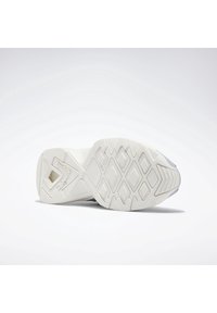 Vit atletisk skosula med strukturerade mönster, med en hexagonal greppdesign, flexibel material och varumärkeslogotyp prägling på sidan.