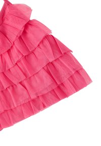 Orlo di un vestito a strati pink realizzato in tulle trasparente con volant. Presenta più strati di volant con un aspetto morbido e testurizzato.
