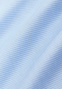 Helles blaues, strukturiertes Gewebe mit einem Gittermuster, das eine glatte Oberfläche und einen subtilen Glanz aufweist und sanft im Bild hängt.