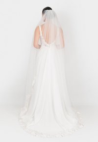 Abito da sposa in chiffon bianco con dettagli in pizzo, schiena profonda e decorazioni floreali sull'orlo. Accompagnato da un lungo velo trasparente.