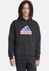 Zwarte hoodie van een katoen-blend stof met een voorvak. Voorzien van een groot wit adidas-logo met blauwe en rode accenten.