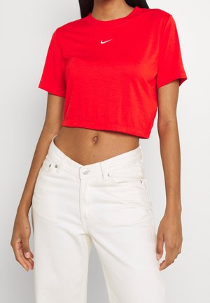 Red cropped t-shirt with short sleeves and a white Nike logo on the chest. Paired with high-waisted white denim jeans.