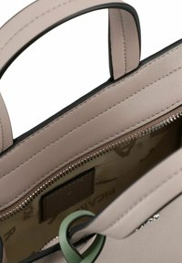 Borsa a mano in pelle beige con texture liscia, chiusura con zip e un accento decorativo verde. L'interno presenta una fodera con motivo.