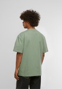 Green short-sleeve t-shirt made of soft fabric, featuring a relaxed fit and crew neckline, shown from the back with casual styling.