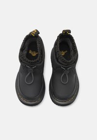 Juodos kulkšninių batų, su lygiu sintetinės medžiagos viršumi, gumuoto apvado, vilkimo kilpute ir geltonu siūlu palei padą. Apskritas raištelių reguliavimo detalė.