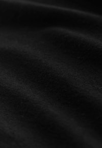 Fekete szövet sima textúrával és finom fényességgel, apró rostokkal és lágy redőkkel. Nincsenek látható mintázatok vagy fémalkatrészek.