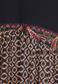 Schwarz-beiges Kleid mit einem gemusterten unteren Abschnitt mit geometrischen Formen und einem verzierten oberen Rand in Rot und Grün. Weicher Stoff.