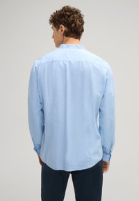 Camicia a maniche lunghe blu chiaro realizzata in tessuto testurizzato, con polsini abbottonati e orlo leggermente curvo. Design slim fit.