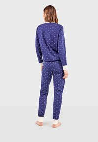 Ensemble de pyjama bleu marine avec un petit motif de cœurs, manches longues et pantalon assorti. Poignets en matériau blanc contrastant.