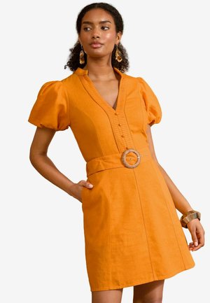Vestido de lino naranja con escote en V, mangas cortas abullonadas, detalles de botones y un cinturón en la cintura con una gran hebilla circular.