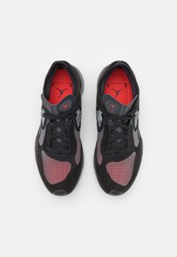 Paire de baskets Nike Air Jordan noires et rouges avec motif en grille, lacets noirs et semelles intérieures rouges ornées du logo Jumpman, vue de dessus.