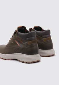 Botas de cuero marrón hasta el tobillo con acentos grises, ante texturizado, costuras naranjas y una suela de goma blanca. Cuenta con un collar acolchado para mayor comodidad.