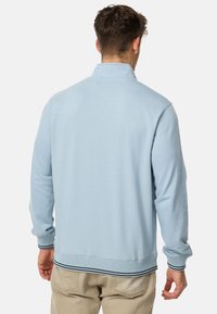 Pull-over bleu clair avec un col montant, des poignets et un ourlet côtelés. Texture douce avec une finition unie et des accents noirs contrastants.