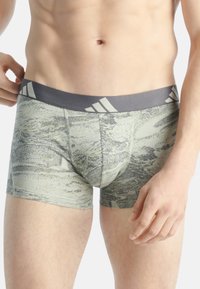 Zelené a šedé boxerky s potiskem, mají elastický šedý pas s třemi bílými pruhy a úzký střih.
