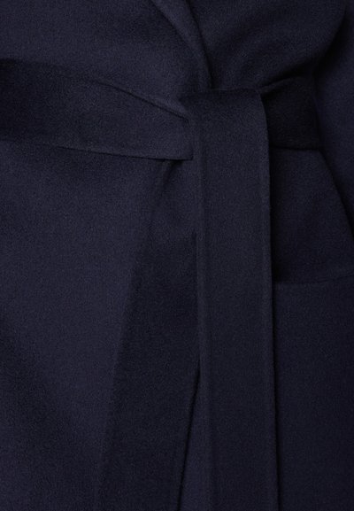 Tessuto in misto lana blu navy con una superficie morbida, caratterizzato da una cintura annodata in vita e una tasca laterale per un tocco di dettaglio in più.