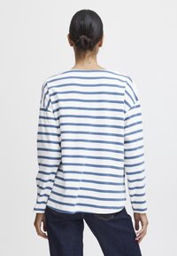 Gestreiftes Langarmshirt in Weiß und Blau, mit lockerem Schnitt, überschnittenen Schultern und weiter Ausschnitt. Aus weichem Baumwollmaterial, lässiges Design.