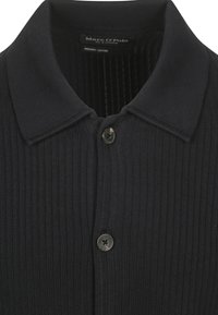 Schwarzes geripptes Poloshirt aus Bio-Baumwolle mit einem klassischen Kragen und einer einzigen Knopfleiste. Texturiertes Gewebe mit matter Oberfläche.