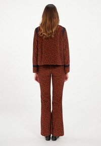 Ensemble deux pièces évasé en rouge et bleu marine avec un motif floral ; haut court et pantalon ajusté avec poches latérales. Tissu doux, design décontracté.