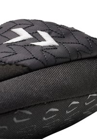 Czarne, wyściełane buty z teksturowanym materiałem, z białym zygzakowatym przeszyciem i wzorzystą podeszwą. Zbliżenie podkreśla materiały i design.