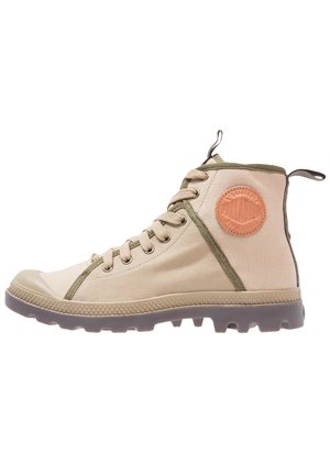 Beżowy sneaker za kostkę z płótna z brązową gumową podeszwą, zielonym wykończeniem, sznurowadłami, pętelkami i okrągłą skórzaną naszywką z logo na kostce.