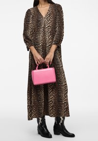 Vestido maxi de estampado de leopardo, bolso texturizado rosa, botas de cowboy negras. El vestido tiene mangas largas y un escote en V; el bolso presenta un diseño estructurado.