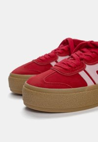 Baskets en daim rouge avec une semelle épaisse en gomme texturée et des accents en cuir rose. Le design à lacets comprend une languette rembourrée et des détails cousus.