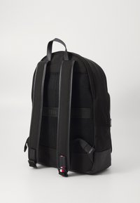 Zaino nero con una finitura in tessuto liscio, schienale in rete per traspirabilità, spallacci regolabili e un accento colorato a contrasto sui lati.